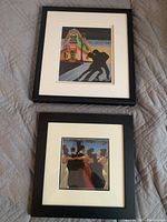 Two professionally matted and framed art prints showing dancing couples, lying flat on a gray surface
