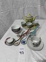 Full view of Asian tea pot, three tea cups on platter, four small bowls, four soup spoons, and one teacup with saucer.