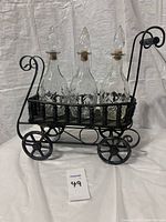 Front view of iron and wood bar cart holding three glass decanters with decorative patterns.