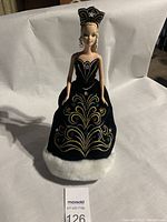 Front view of Holiday Barbie doll in black Christmas tree dress with gold embroidery and rhinestones, white fur trim, and headpiece