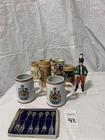 Photo of all beer steins, Irish liquor bottle figurine, and boxed set of dessert forks.