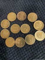 Top-down view of 12 commemorative Canadian provincial coins arranged on a dark fabric background showing the front sides with provincial plaques and shields.