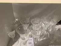 Front view showing multiple crystal wine glasses with clear cornflower patterns etched through the glass, grouped and arranged on a flat surface.