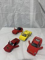 Four die cast cars on display showing the yellow Lamborghini Countach, two Ferrari models, and the smaller Firebird car with the doors open on some cars.