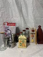 Overview of the kitchen items including stainless steel canisters, glass jars, wooden spice racks, and boxed Sunbeam cookware.
