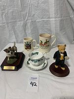 Lot contents with two mugs, teacup and saucer, dog and bear figurines on display