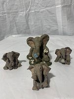 Four gray Tusker elephant figurines with textured surfaces and floral decorations on one statue