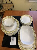 Photo showing the stacked bowls, dinner plates, sandwich plates, and two serving pieces with vintage Noritake Sun Glow design in yellow and gold geometric pattern around the rims.