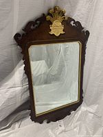 Full view of the vintage wooden framed mirror with gold accent at the top.