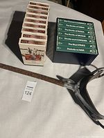 Photo showing two stacks of VHS tapes from 'The World at War' and 'Readers Digest Different War History' series alongside a military metal trench seat with carrying strap.