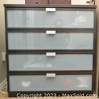 Photo of a modern low dresser with four frosted glass panel drawers and rectangular metal handles.
