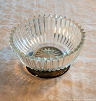 Clear glass salad bowl on a patterned tablecloth, showing fluted vertical ridges and starburst design at base.