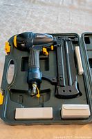 Air powered finish nailer, brad nailer, and stapler tool with carrying case, showing main tool placed in case with side compartments for accessories.