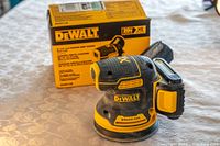 DeWalt 5 inch random orbital sander with 20V XR brushless motor, placed on table with original box behind it.