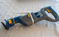Photo of a blue and gray Maximum reciprocating saw with orange button accents, showing the saw in profile.