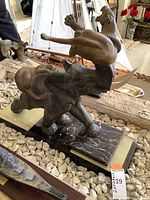 Side angle showing elephant mid-stride with a lioness clinging to its raised trunk