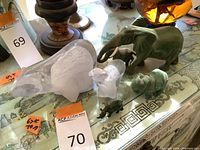 Photo showing large and small clear glass or crystal polar bear sculptures on a glass table with decorative table surface and other items blurry in background.