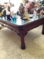 Side and leg view showing detailed carvings and reddish-brown wood with slight sun fading.