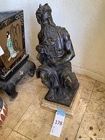 Front and right view of bronze statue of kneeling bearded male figure on wooden base