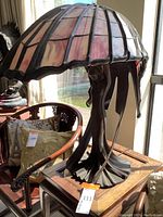 Front three-quarter view of figural lamp with stained glass shade