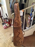 Side view of the leather gun case showing the embossed floral and horse design with handle on top.