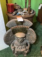 Full view of cast metal statue in front of table with accessories