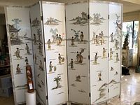 Full front view of the six-panel folding room divider showing white lacquered panels with scenic paintings and plastic figurines.