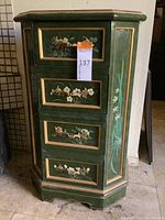 Front view of green octagonal side table with four drawers and floral motifs