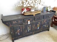 Full front view of black lacquered sideboard with handpainted figures and metal hardware
