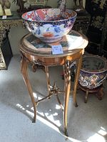 Full view of wooden table with round tiled top and large Asian bowl on top in room setting