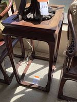 Full view of wooden table with carved legs and inset rectangular tabletop panel. Displays overall shape and details.