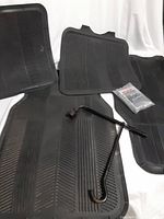 Four black rubber car mats laid out with iron tire torque wrench and emergency rescue blanket packaged.
