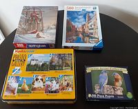 Photo showing 4 puzzle boxes stacked: Springbok winter bird; Ravensburger Venetian canal; Kodacolor Photo Gallery; Famous Artist birds.
