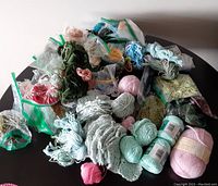 Top view of assorted wool balls and wool bits spread on a table with multiple plastic bags.