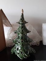 Front view of vintage ceramic Christmas tree with intricate leaf cutouts and original packaging around it.