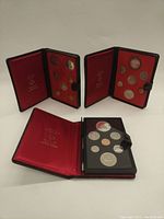 Photo of three Royal Canadian Mint double dollar coin sets in black leather cases with red interior lining.