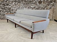 Full front side view of the long blue textured sofa with teak wood armrests and legs, showing overall shape and condition.