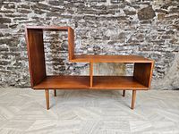 Front view of shelving unit against stone wall on light floor showing overall design and condition