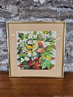 Framed watercolour painting showing colorful leaves and white flowers.