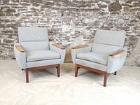 Pair of teak armchairs side by side against stone wall, front view
