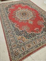 Full view of the Persian style carpet showing medallion and floral patterning in red, black, blue and cream colors.