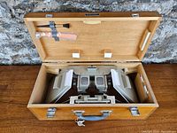 View of the open wooden case containing the stereometer bar and a cleaning brush mounted inside the lid.
