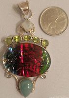 Front view of large multi-colored oval stone pendant in 925 silver with additional small green stones and diamond-shaped stone.