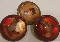 Close-up of two brass brooches with horse heads under reddish resin and one with Victorian female portrait under clear resin.