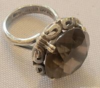 Close-up view of the faceted smoky quartz stone set in an ornate sterling silver bezel with swirl designs.