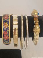 Photo showing full view of all five bangles and the clamper bracelet on a display stand.