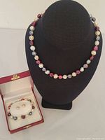 Full set displayed including a necklace on a black bust and the bracelet with earrings in a red jewelry box.