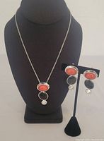 Full view of necklace on display stand alongside matching earrings on separate stand, showing overall look and scale.