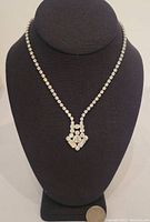 Front view of the rhinestone necklace displayed on a black bust showing clear rhinestones and decorative pendant detail.