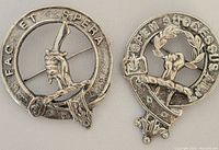 Two metal pins, one round with hand and sword, inscribed 'FAC ET SPERA', the other oval with fist and laurel wreath, inscribed 'SPES SUCCESUS ALT'.